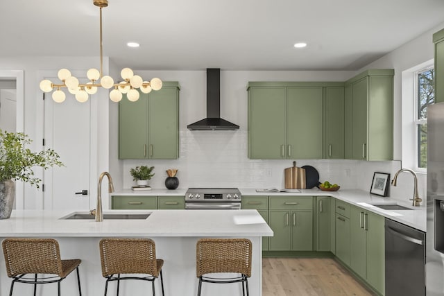 kitchen featuring appliances with stainless steel finishes, sink, wall chimney range hood, and green cabinets