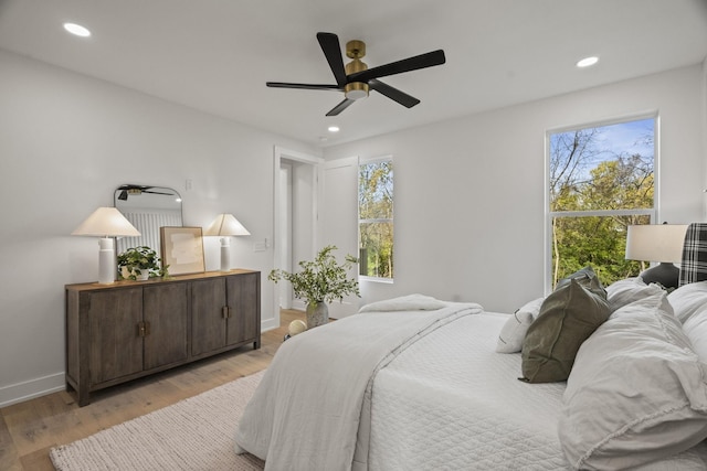 bedroom featuring ceiling fan, light hardwood / wood-style floors, and multiple windows