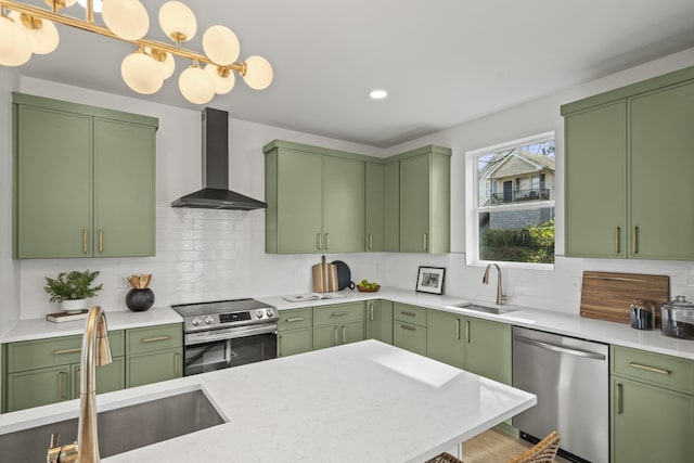 kitchen featuring stainless steel appliances, wall chimney exhaust hood, and green cabinets