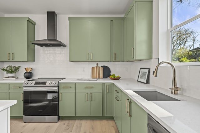 kitchen featuring stainless steel electric range, sink, green cabinets, and wall chimney exhaust hood