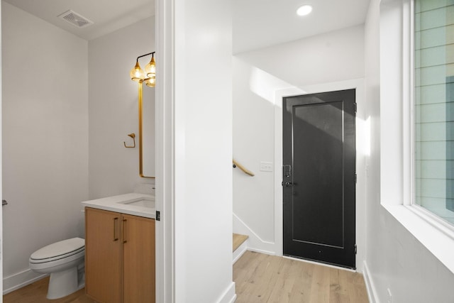 bathroom featuring vanity, wood-type flooring, and toilet