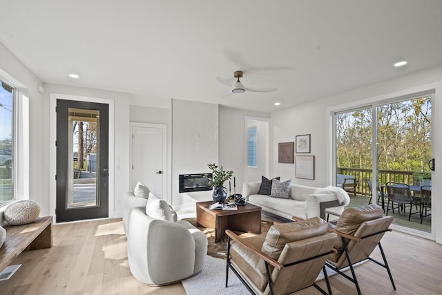 living room with ceiling fan, plenty of natural light, and light hardwood / wood-style floors