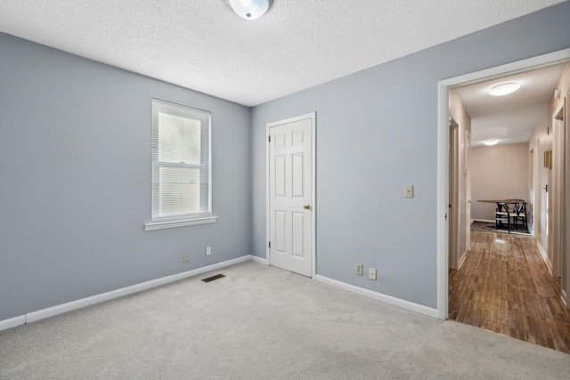 unfurnished bedroom featuring light colored carpet and a textured ceiling