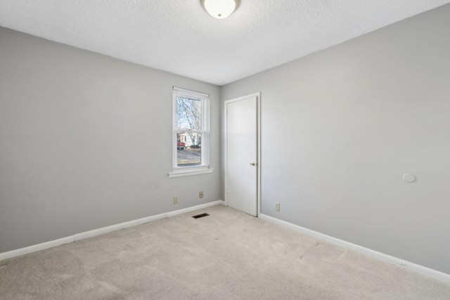 unfurnished room with light carpet and a textured ceiling