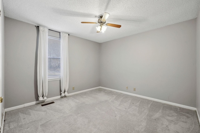 carpeted empty room with ceiling fan and a textured ceiling