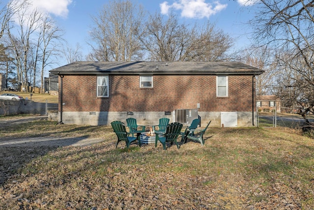 back of property featuring a yard, central AC, and a fire pit