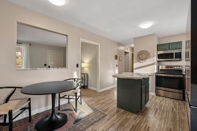 kitchen with hardwood / wood-style flooring, appliances with stainless steel finishes, a center island, and light stone counters