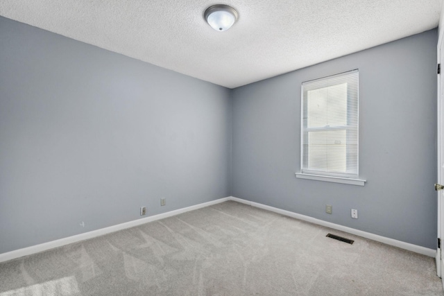 spare room featuring light carpet and a textured ceiling