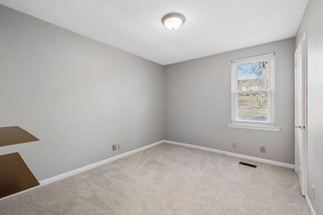 spare room featuring light carpet and a textured ceiling