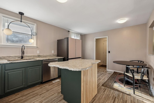 kitchen featuring sink, dishwasher, hardwood / wood-style floors, a kitchen island, and decorative light fixtures