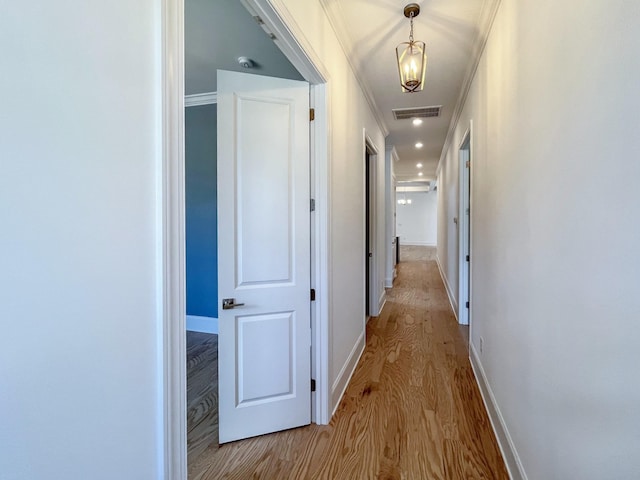 corridor featuring ornamental molding and light hardwood / wood-style flooring