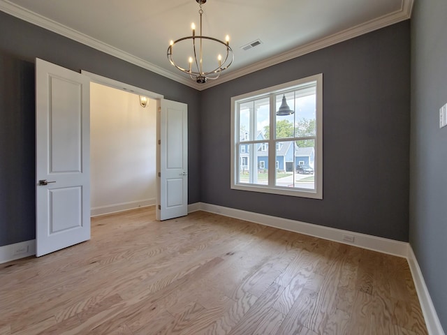 spare room featuring ornamental molding, a chandelier, and light wood-type flooring