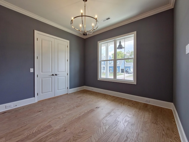 spare room with ornamental molding, a chandelier, and light hardwood / wood-style floors