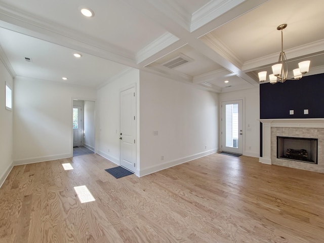 unfurnished living room featuring a tiled fireplace, coffered ceiling, a notable chandelier, light hardwood / wood-style floors, and beam ceiling