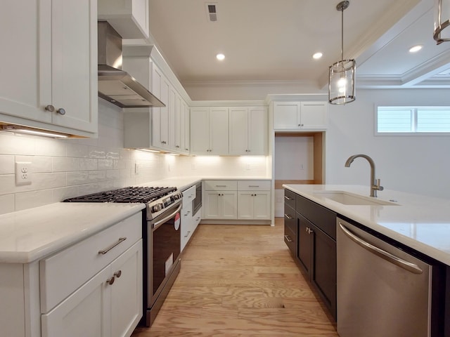 kitchen with stainless steel appliances, white cabinetry, decorative light fixtures, and wall chimney exhaust hood