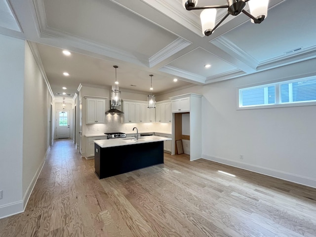 kitchen with pendant lighting, white cabinetry, a kitchen island with sink, wall chimney range hood, and beam ceiling