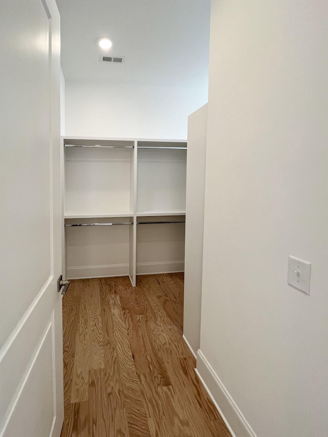 walk in closet with light hardwood / wood-style flooring