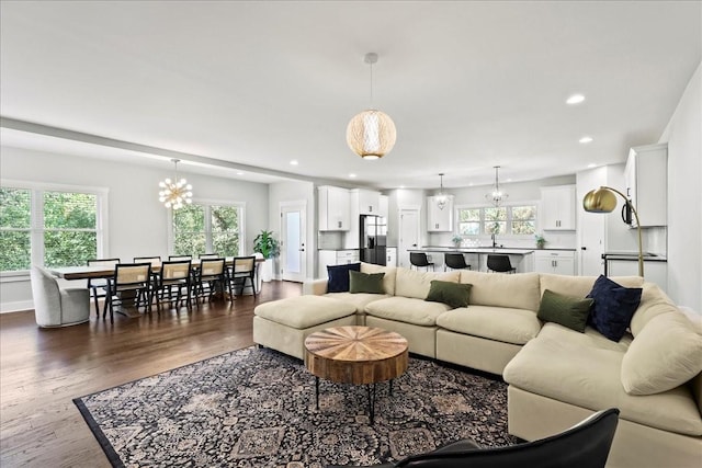 living room featuring dark wood-type flooring, sink, and an inviting chandelier