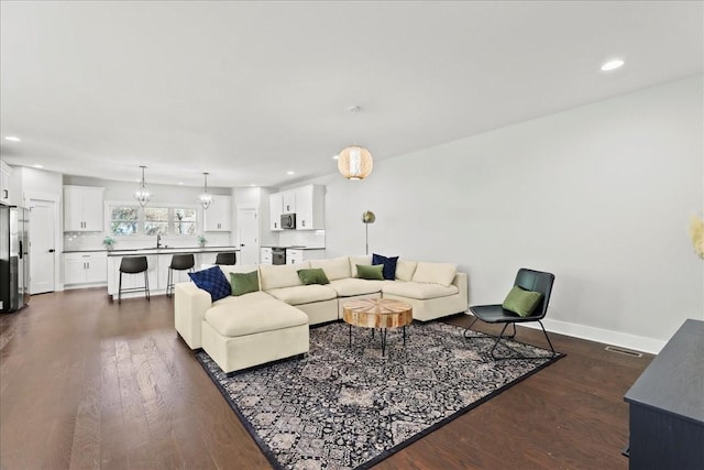 living room with dark wood-type flooring, sink, and a notable chandelier