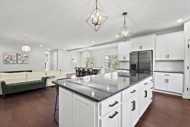 kitchen featuring hanging light fixtures, stainless steel refrigerator with ice dispenser, a kitchen island, and white cabinets