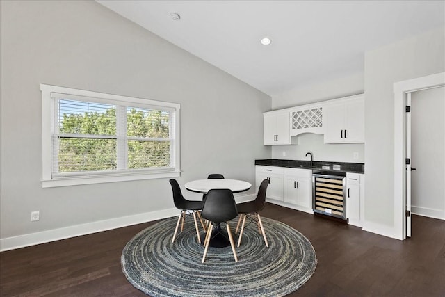 dining room with high vaulted ceiling, dark wood-type flooring, wet bar, and beverage cooler