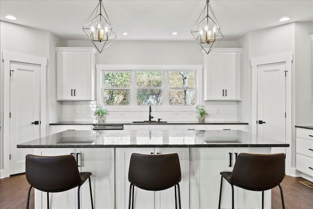 kitchen with sink, white cabinetry, tasteful backsplash, a kitchen island, and pendant lighting