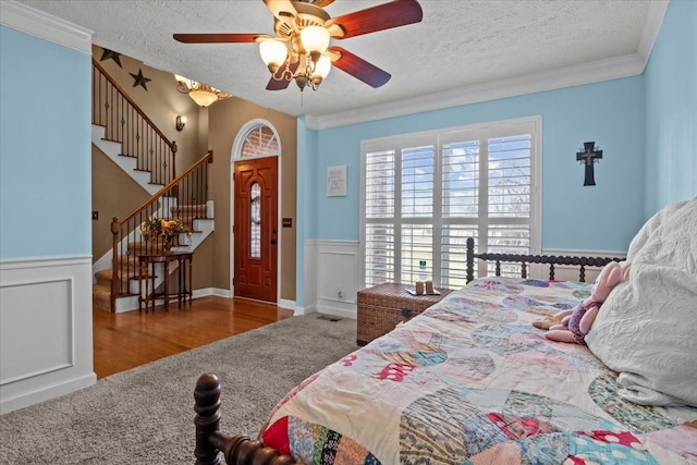 bedroom with ceiling fan, ornamental molding, hardwood / wood-style floors, and a textured ceiling