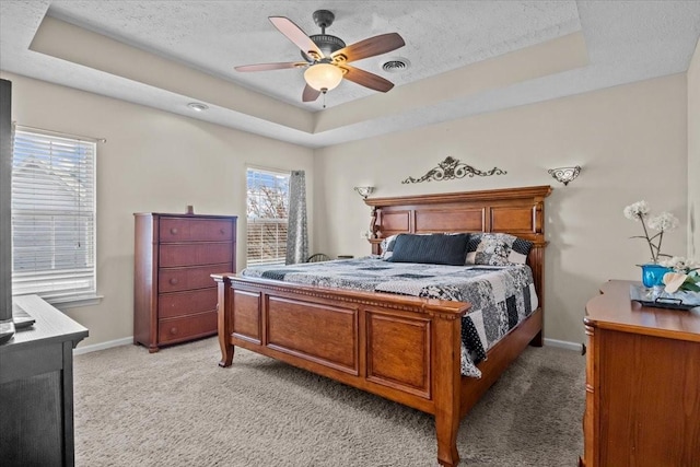 bedroom with ceiling fan, a raised ceiling, and multiple windows