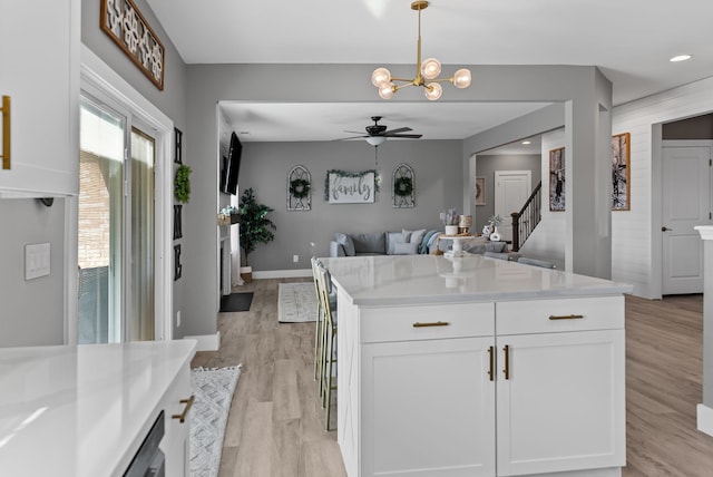 kitchen featuring white cabinetry, hanging light fixtures, ceiling fan with notable chandelier, and light wood-type flooring