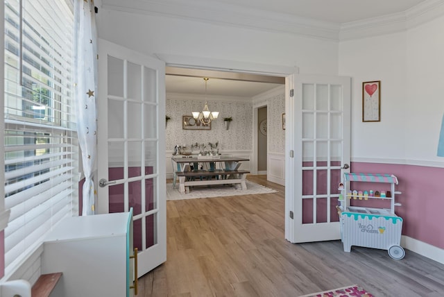 interior space with hardwood / wood-style flooring, ornamental molding, a notable chandelier, and french doors