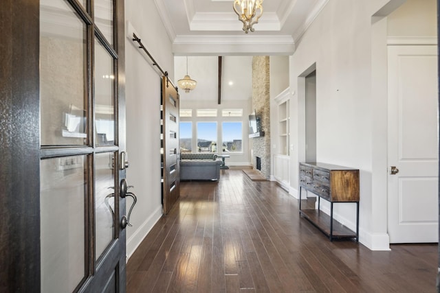 corridor with built in features, dark hardwood / wood-style flooring, a high ceiling, a barn door, and an inviting chandelier