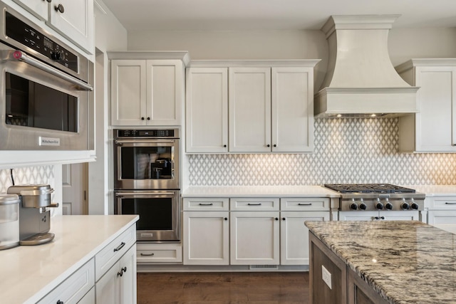 kitchen with white cabinetry, backsplash, stainless steel appliances, dark wood-type flooring, and wall chimney exhaust hood