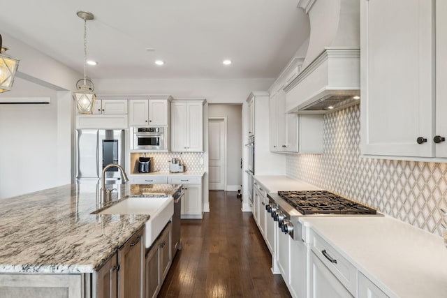 kitchen with white cabinetry, a kitchen island with sink, premium range hood, and appliances with stainless steel finishes