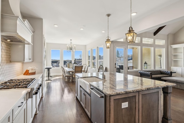 kitchen with custom range hood, pendant lighting, white cabinets, and decorative backsplash