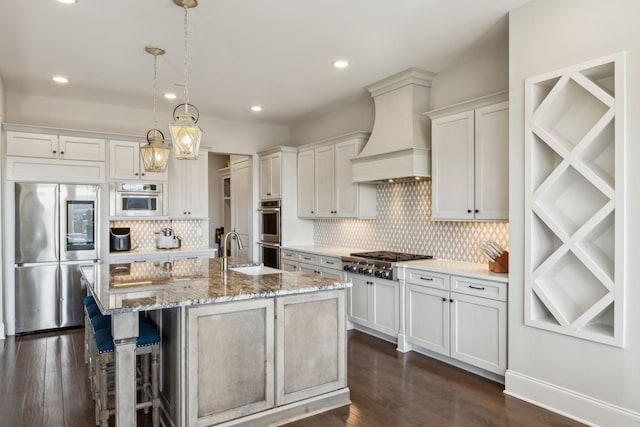 kitchen with a kitchen breakfast bar, stainless steel appliances, custom range hood, white cabinets, and a center island with sink