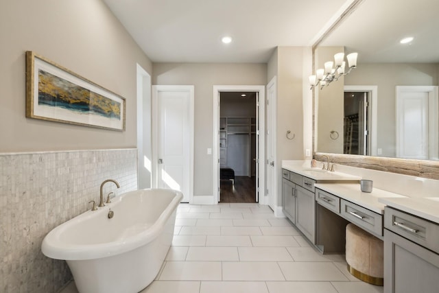 bathroom with tile patterned floors, vanity, a bath, and tile walls