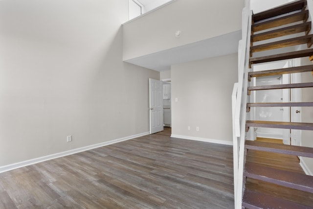 stairs with wood-type flooring and a high ceiling