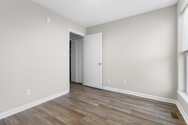 unfurnished bedroom with multiple windows and hardwood / wood-style floors