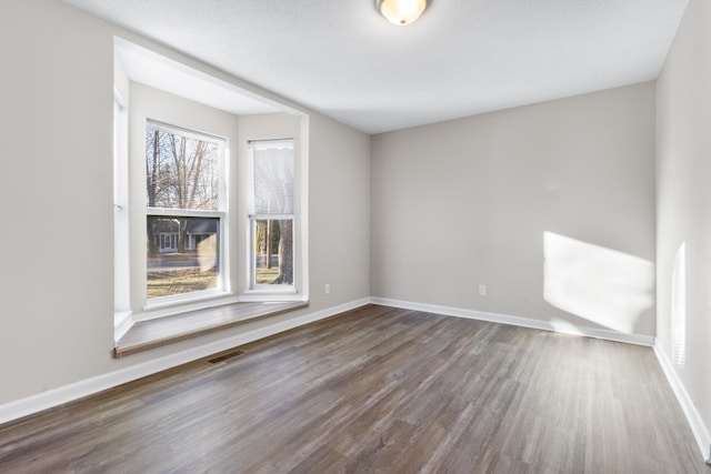 unfurnished room featuring a wealth of natural light and dark hardwood / wood-style floors