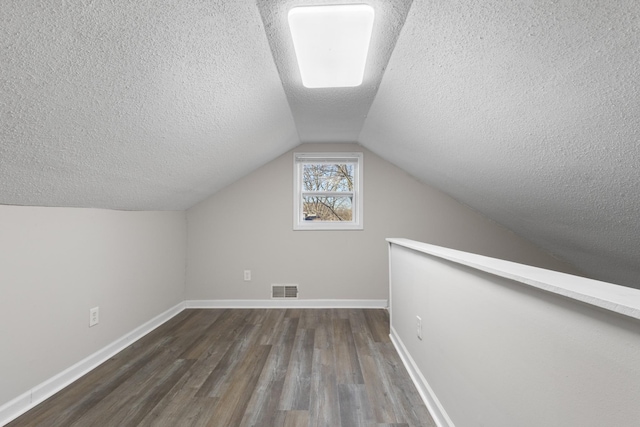 bonus room featuring vaulted ceiling, dark wood-type flooring, and a textured ceiling