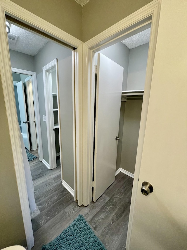 hallway with dark wood-type flooring and a textured ceiling