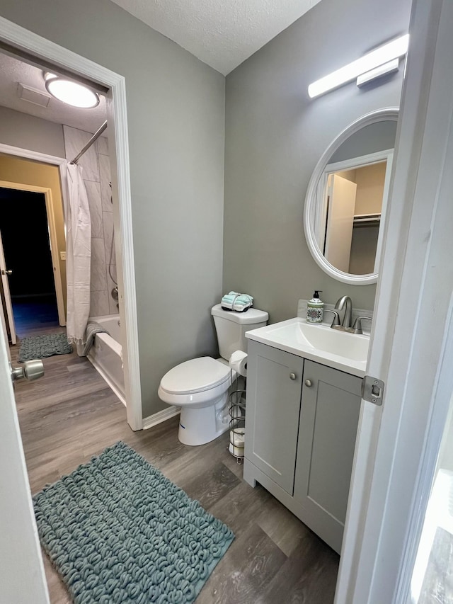 full bathroom featuring toilet, shower / tub combo, a textured ceiling, vanity, and hardwood / wood-style flooring