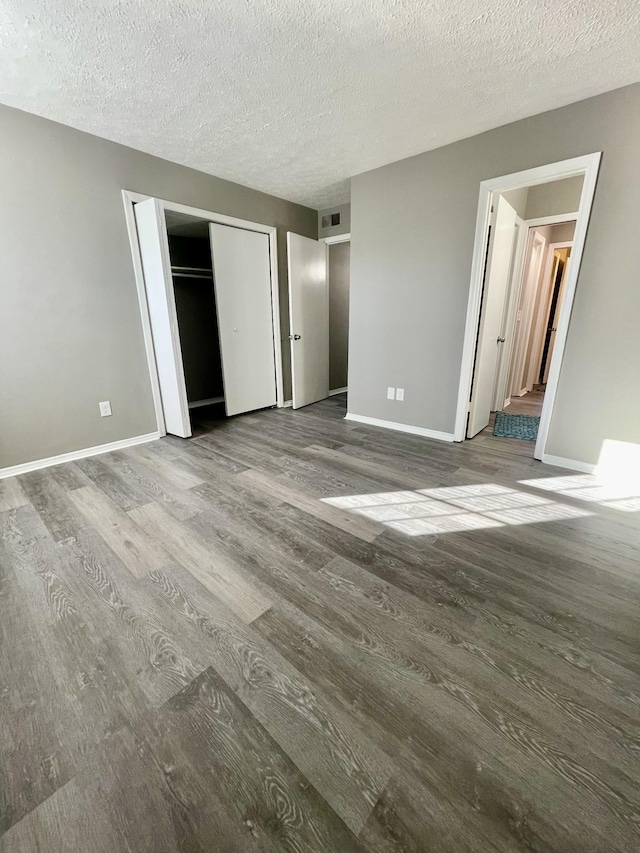 unfurnished bedroom with wood-type flooring, a textured ceiling, and a closet