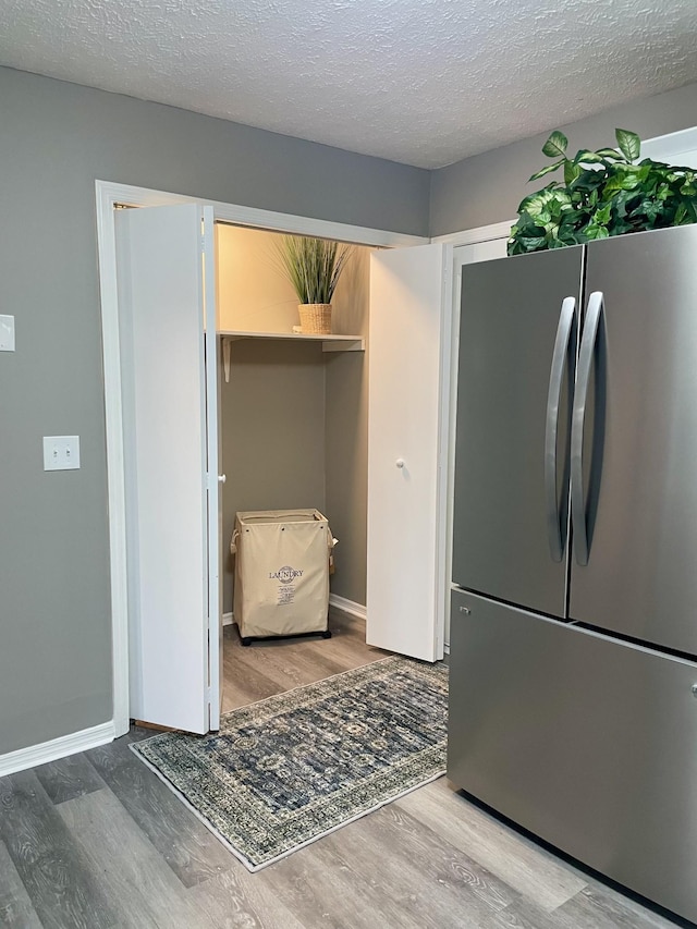 kitchen featuring hardwood / wood-style floors, stainless steel fridge, and a textured ceiling