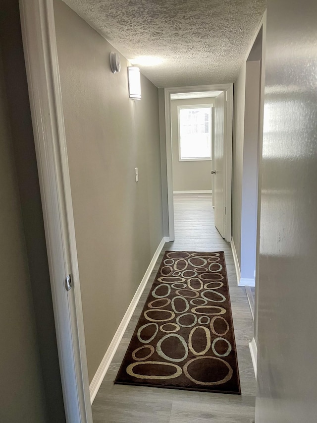 hall with hardwood / wood-style flooring and a textured ceiling