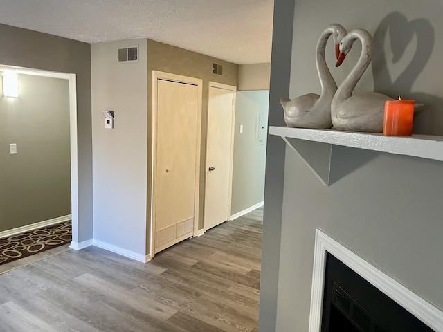 hallway with a textured ceiling and light wood-type flooring