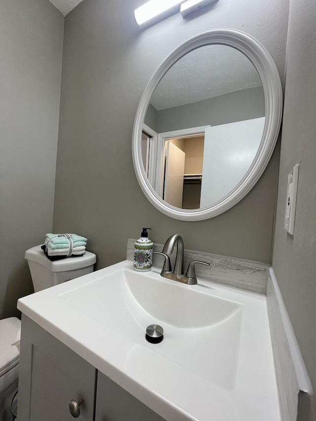 bathroom featuring vanity, a textured ceiling, and toilet