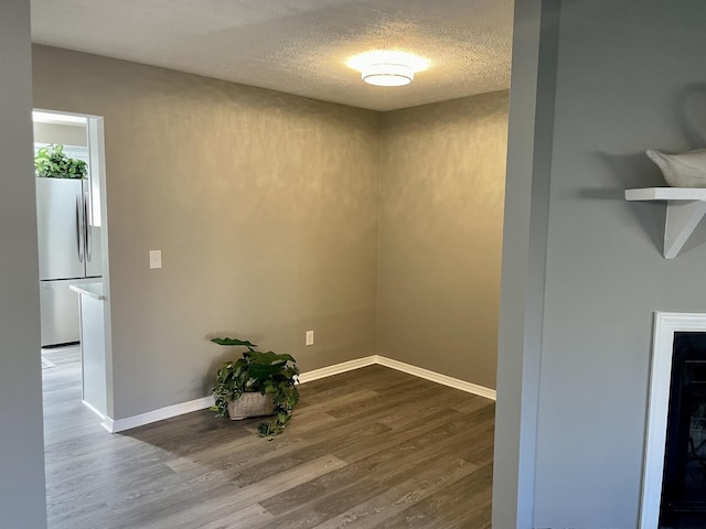 spare room with wood-type flooring, a fireplace, and a textured ceiling