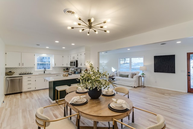 dining space with plenty of natural light, a chandelier, sink, and light hardwood / wood-style flooring