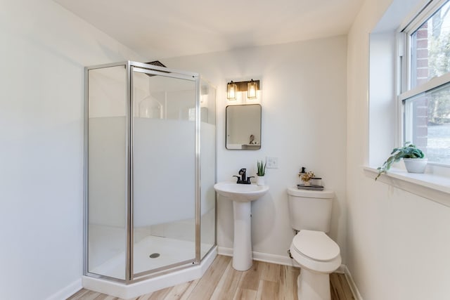 bathroom with hardwood / wood-style flooring, a shower with shower door, and toilet